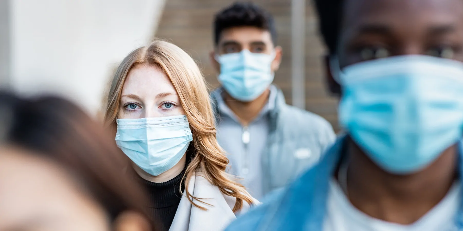 WHO Updates COVID-19 Guidelines People in a line facing the camera wearing medical face masks