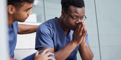 A stressed health care worker being comforted by a colleague