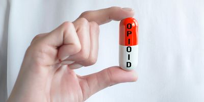Person holding a fake, oversized pill that says "Opioid"