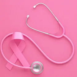 A pink ribbon and stethoscope on a pink background