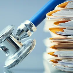 A stethoscope on a pile of paperwork