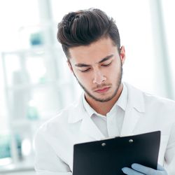 Photo of a clinical lab professional holding a clip board conducting a lab inspection.