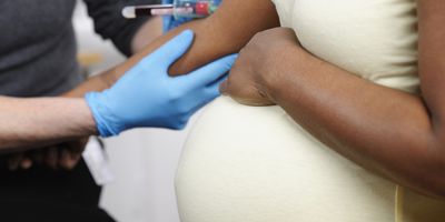 A close-up of a clinician collecting blood from a pregnant woman
