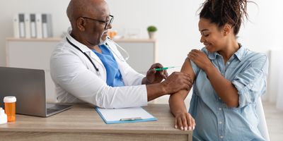 Smiling Pregnant Black Woman Getting Vaccinated In Doctor's Office