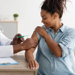 Smiling Pregnant Black Woman Getting Vaccinated In Doctor's Office