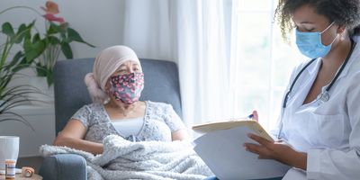 African-American female doctor wearing a mask while talking to a female cancer patient