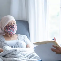 African-American female doctor wearing a mask while talking to a female cancer patient