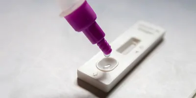 Antigen test sample being dropped onto a medical device for a self, at-home test.