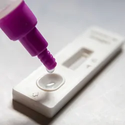 Antigen test sample being dropped onto a medical device for a self, at-home test.