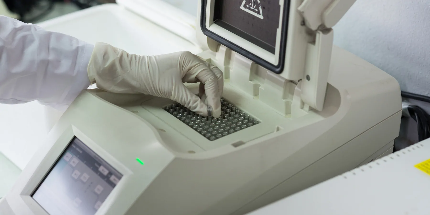 Ultrafast PCR to Revolutionize Precision Diagnosis Close-up of technician with gloved hand placing sample vials into a PCR thermocycler.
