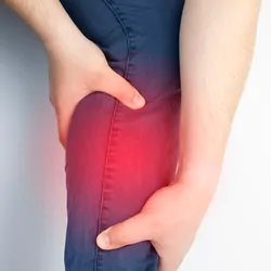 A man holds an aching calf muscle as the area is highlighted in red.