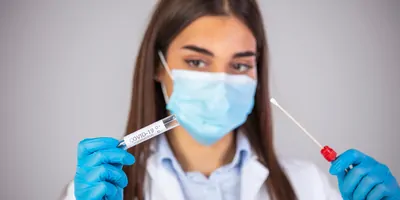 Lab personnel holding a sample collection device, or swab, in her gloved hands.