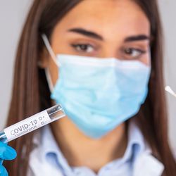 Lab personnel holding a sample collection device, or swab, in her gloved hands.