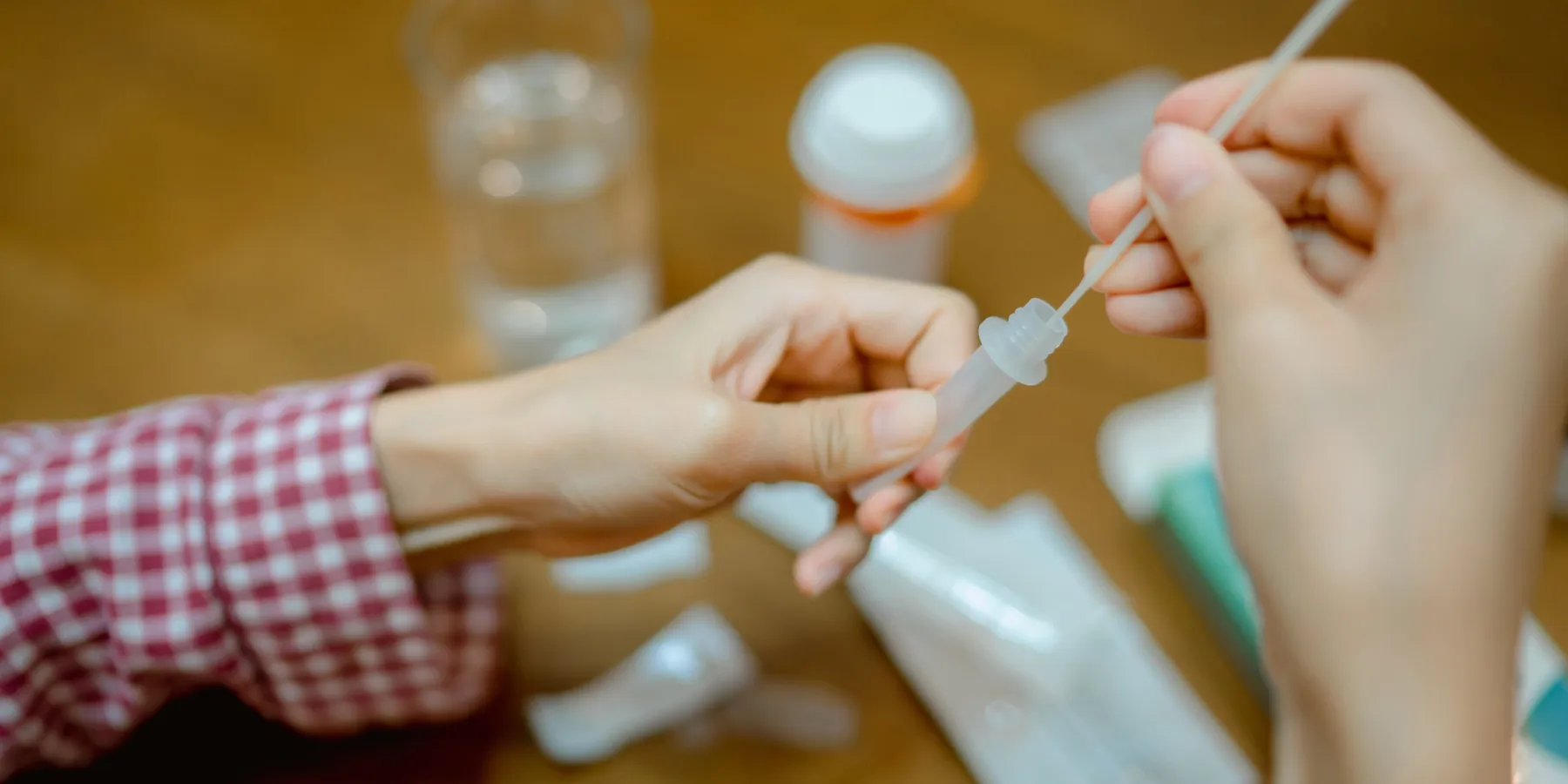 A person drops a nasal swab in a protective plastic tube to test for coronavirus infection, at home