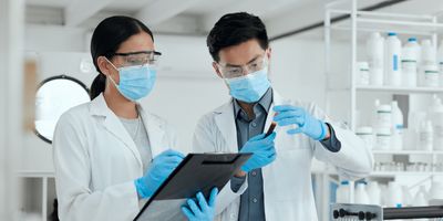 Close-up of a female and a male researcher with PPE reviewing a test sample together