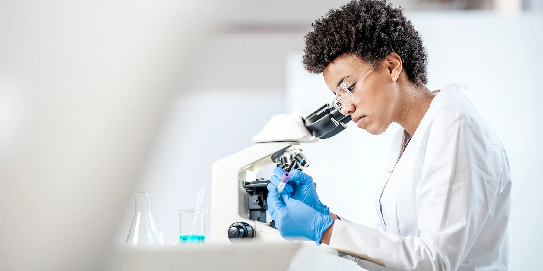 Nobel Laureate to Receive 2023 AACR Award for Outstanding Achievement in Chemistry in Cancer Research A young female scientist wearing PPE looks into a microscope.