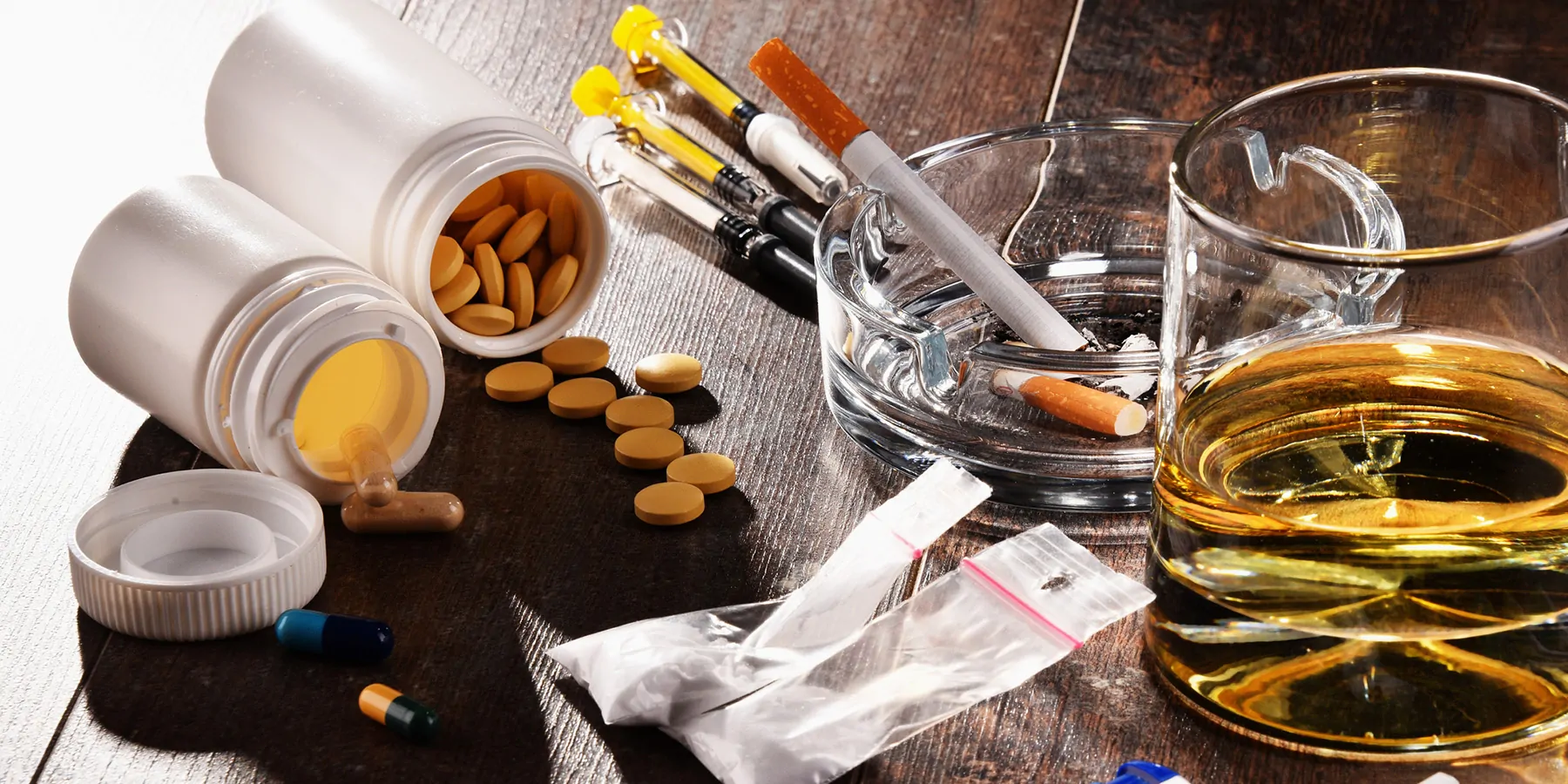 Close-up of addictive substances, including alcohol, cigarettes, and drugs.