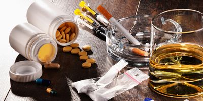 Close-up of addictive substances, including alcohol, cigarettes, and drugs.