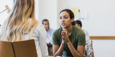 A female counselor listens to a stressed and anxious mid-adult female soldier.