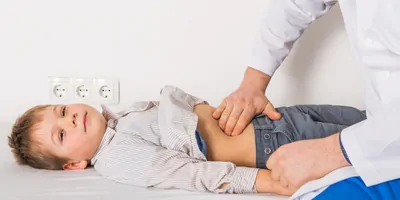 A doctor examines the belly of a child at a clinic.