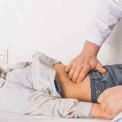 A doctor examines the belly of a child at a clinic.