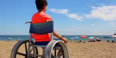 A boy in a wheelchair looks at the blue sea