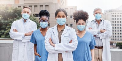 Shot of a group of doctors standing with their arms crossed in the city.