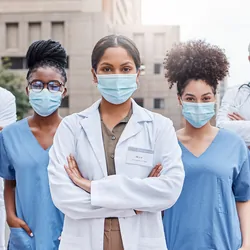 Shot of a group of doctors standing with their arms crossed in the city.