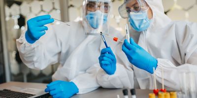 Two medical workers working with covid19 samples. Both are dressed in full PPE.