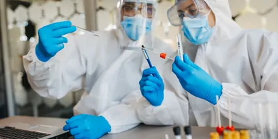 Two medical workers working with covid19 samples. Both are dressed in full PPE.
