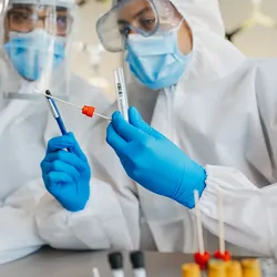 Two medical workers working with covid19 samples. Both are dressed in full PPE.