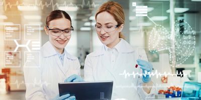 Clever enthusiastic positive doctors feeling glad while standing in their modern equipped laboratory and looking at the screen of a tablet