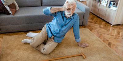 Senior man with walking stick lying on carpet at home. faint, stroke, accident or other health problem