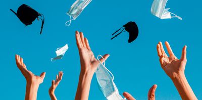 Hands throw protective masks in the air celebrating the end of pandemic