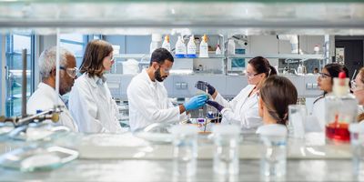 Photograph of a group of clinical lab professionals in white lab coats gathered in a laboratory as part of a certified, hands-on training program.