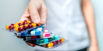 Pharmacist or doctor's hand holding pack of antibiotic capsule pills and giving patient or people.