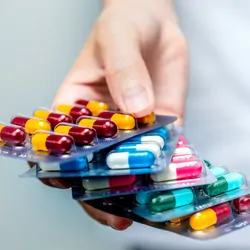 Pharmacist or doctor's hand holding pack of antibiotic capsule pills and giving patient or people.