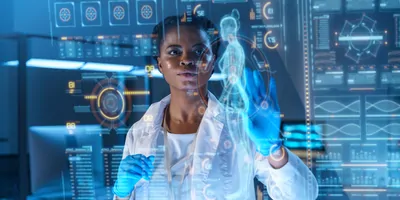A young female clinician works on a graphic display with several health care-related icons in a modern laboratory.