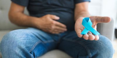 A man holding a blue prostate cancer awareness ribbon in hand