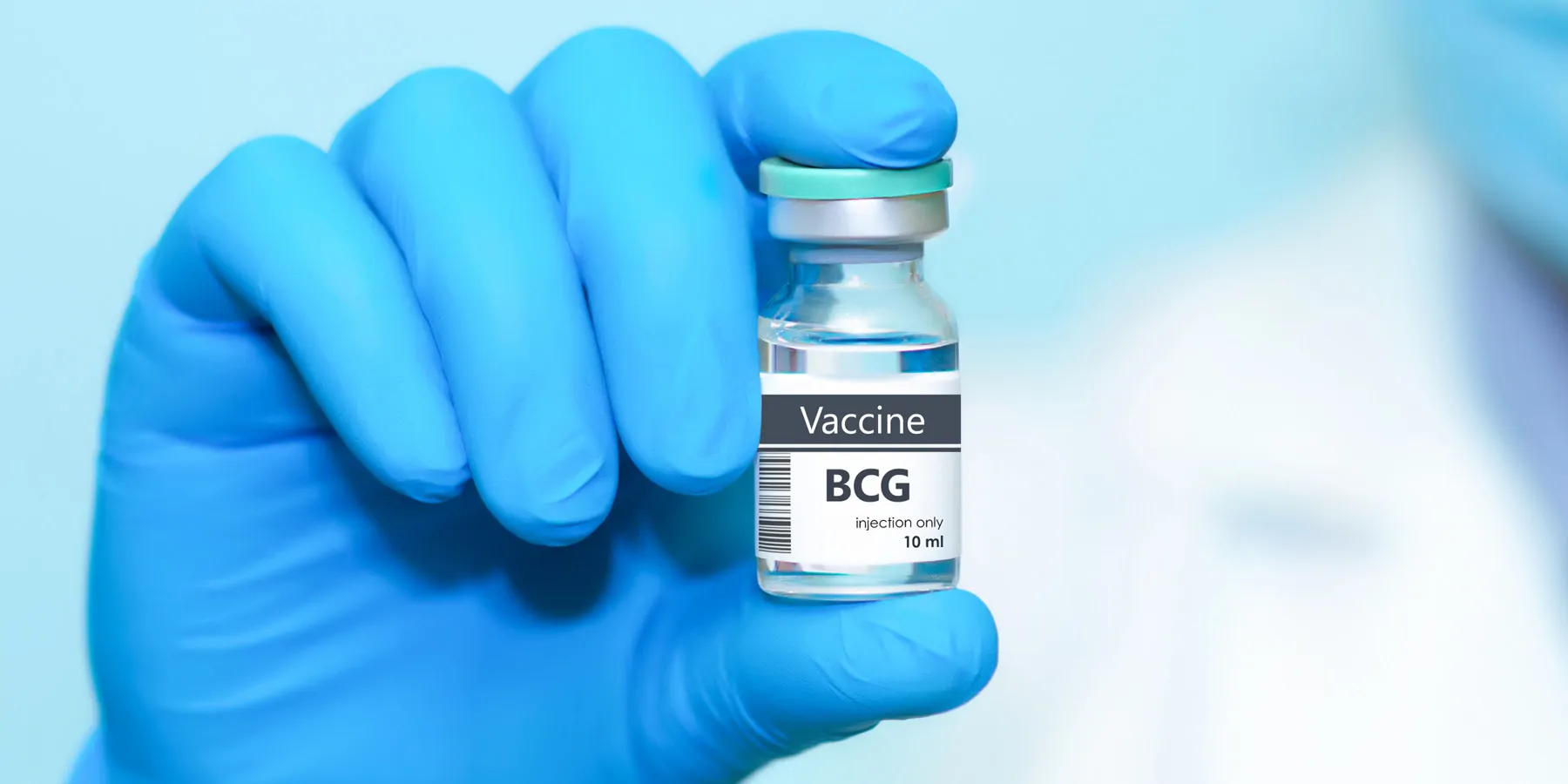 Clinician in protective gloves holding a BCG (tuberculosis) vaccine vial.