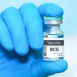 Clinician in protective gloves holding a BCG (tuberculosis) vaccine vial.