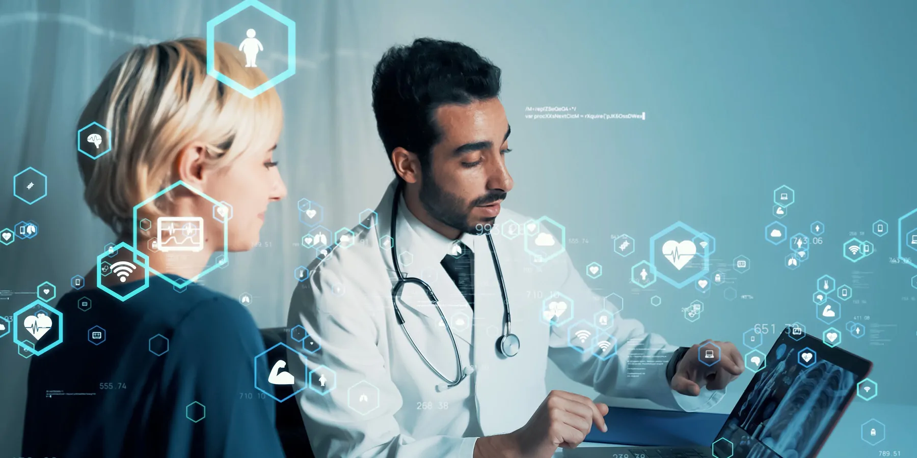 A male clinician discusses a medical report with a woman and points to a screen.