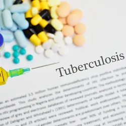 A gloved hand holds a loaded syringe with tablets and capsules and Tuberculosis text printed in the background