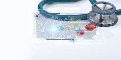 Electronic display showing human body divided into specific components with light shining from the center. Teal stethoscope displayed in the background behind display on a white surface.