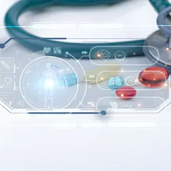 Electronic display showing human body divided into specific components with light shining from the center. Teal stethoscope displayed in the background behind display on a white surface.