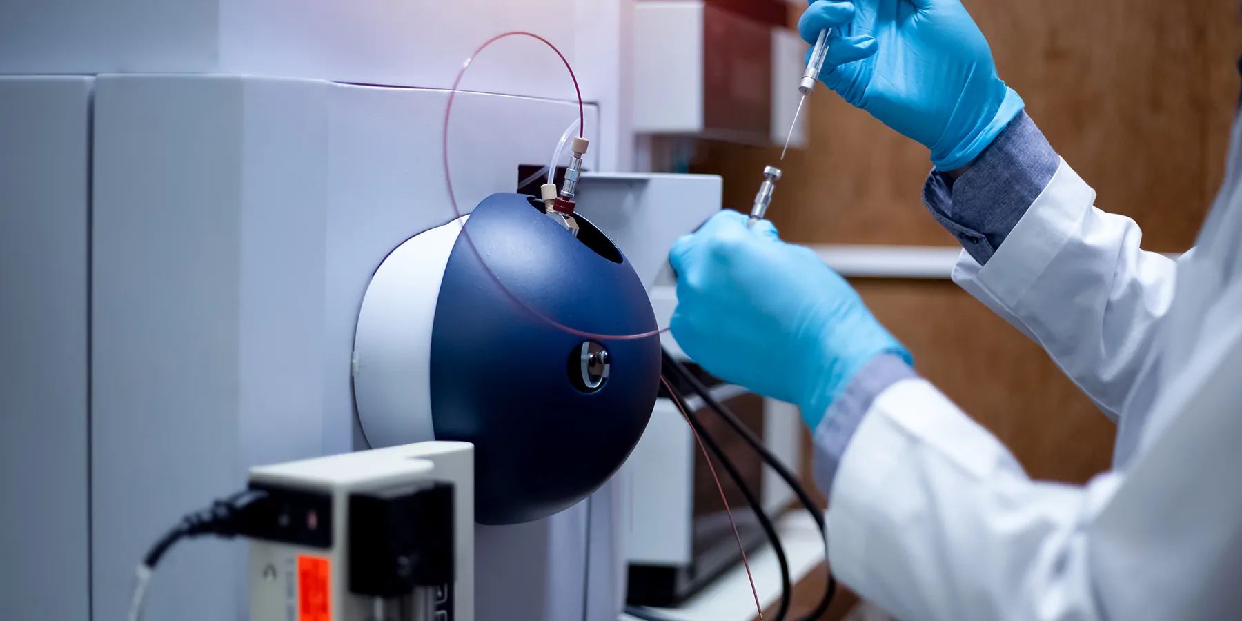 A clinical lab professional injects a sample into a time-of-flight mass spectrometer for analysis in a medical laboratory. A clinical lab professional injects a sample into a time-of-flight mass spectrometer for analysis in a medical laboratory.