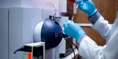 A clinical lab professional injects a sample into a time-of-flight mass spectrometer for analysis in a medical laboratory.