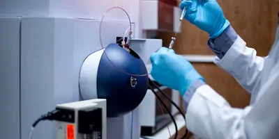 A clinical lab professional injects a sample into a time-of-flight mass spectrometer for analysis in a medical laboratory.