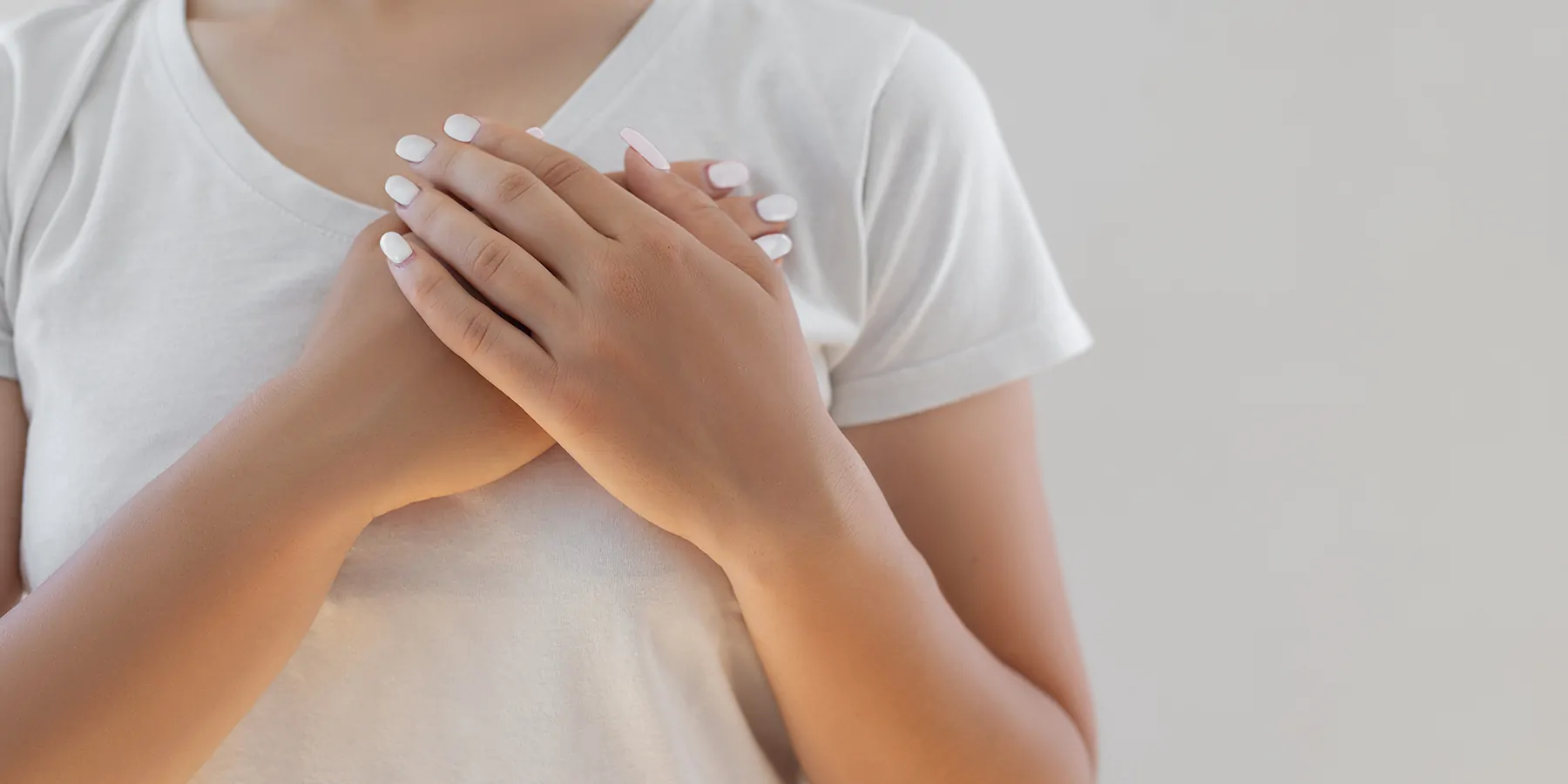 A woman places her palms one over the other on her left breast