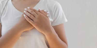 A woman places her palms one over the other on her left breast